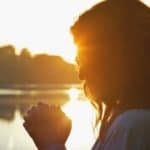 Woman praying by a lake. Short prayers for mothers at Hope Filled Faith.