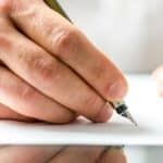 sending hugs and prayers - a person holding a calligraphy pen, getting ready to write on a blank sheet of paper