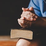 Praying for your husband in difficult times - (7) - picture of woman sitting on bench praying with Bible