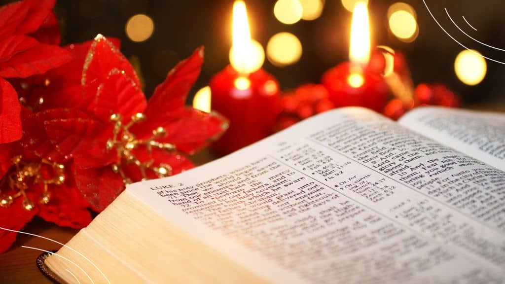Advent Bible Reading Plan - (6) open Bible against background of lit candles and Christmas flowers