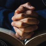 Prayers for Feeling Overwhelmed (6) 1 set of hands clasped in prayer inside of a Bible