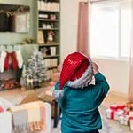 3 - Christian letter from Santa - child with Santa hat standing in front of the Christmas tree