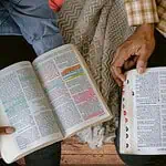 31 scriptures to pray for your family - 2 people praying with their Bibles open on a couch