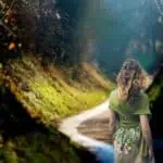 3 - woman standing on a sunlit path - Bible verses about Jesus being the light