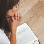 3 - woman praying with open Bible - Bible verses about God's power