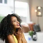 woman praying and smiling in cozy living room - nurturing a thankful heart